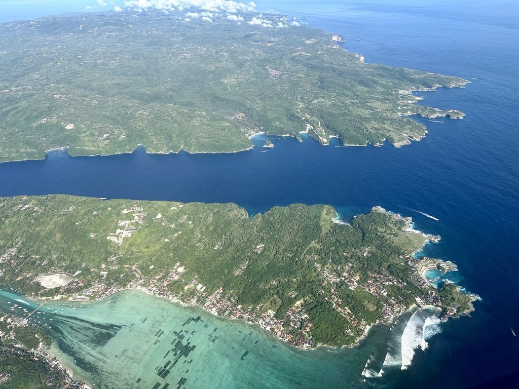 Vue aérienne de Nusa Ceningan avec Nusa Penida en arrière-plan de l'autre côté d'un chenal turquoise