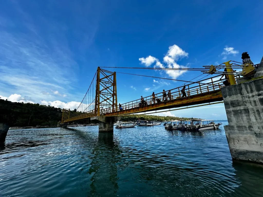 Le pont piéton jaune reliant Nusa Lembongan et Nusa Ceningan au-dessus d'un chenal turquoise